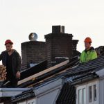 Workers operate on a rooftop under construction in the Netherlands, showcasing teamwork and safety.