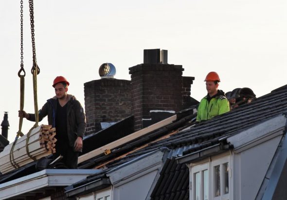 Workers operate on a rooftop under construction in the Netherlands, showcasing teamwork and safety.